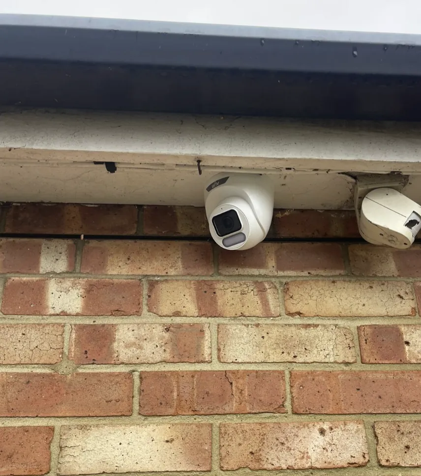 Two CCTV cameras mounted neatly under a soffit on a brick house